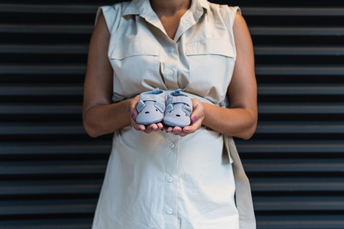 Anonymous Black woman showing baby booties