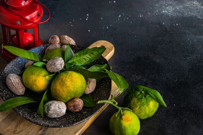 Green tangerines in grey ceramic bowl with walnuts