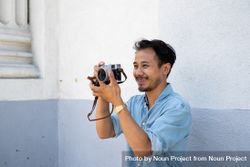 Asian photographer smiling and holding a camera away from face 5r9lP0
