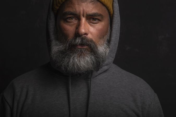 Portrait of middle aged man with gray hoodie with gloomy expression against
