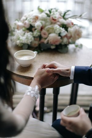 Cropped image of bride and groom sitting and holding hands