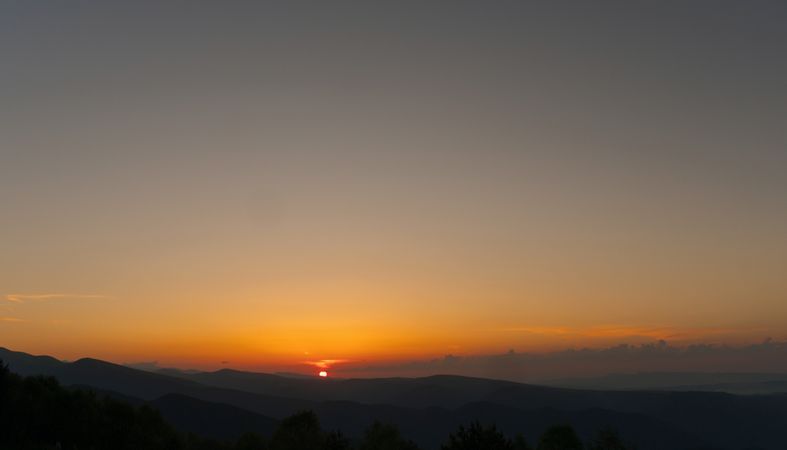Golden sunset over mountains with clear sky.