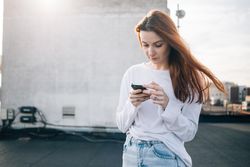 Red haired woman texting on roof