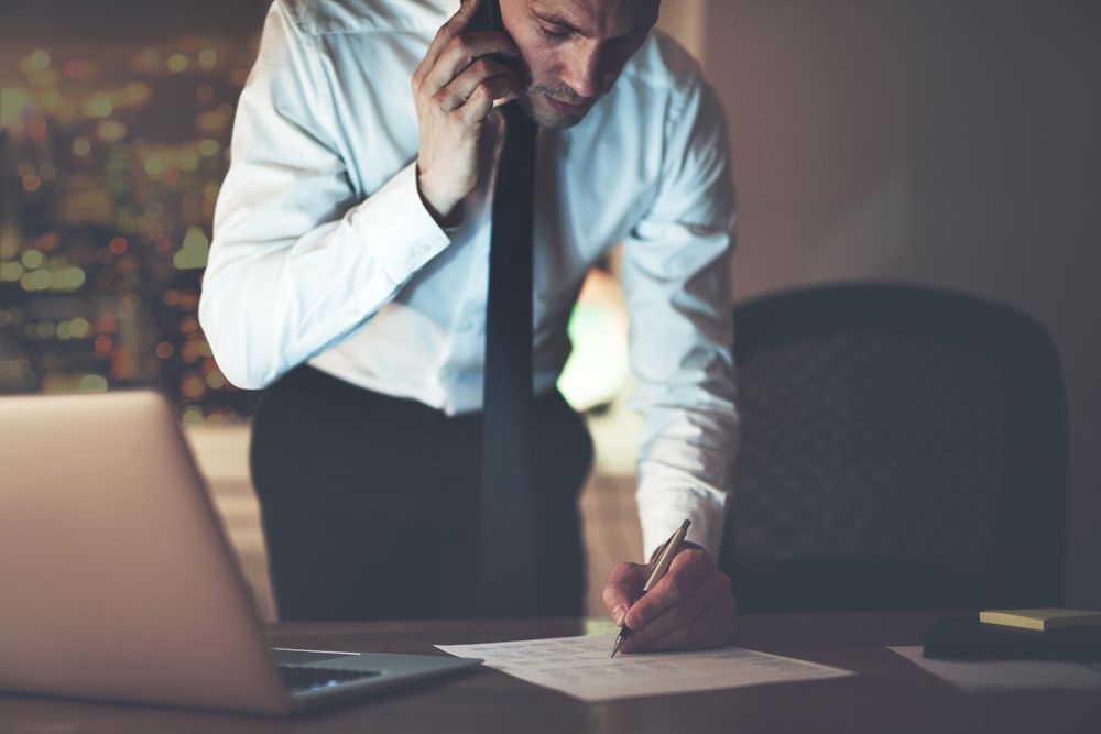 Professional man speaking on his phone while writing on documents