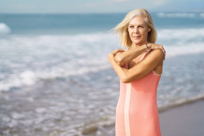 Older woman wrapping her arms around herself on the coast