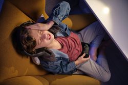 Upset boy playing videogame in armchair