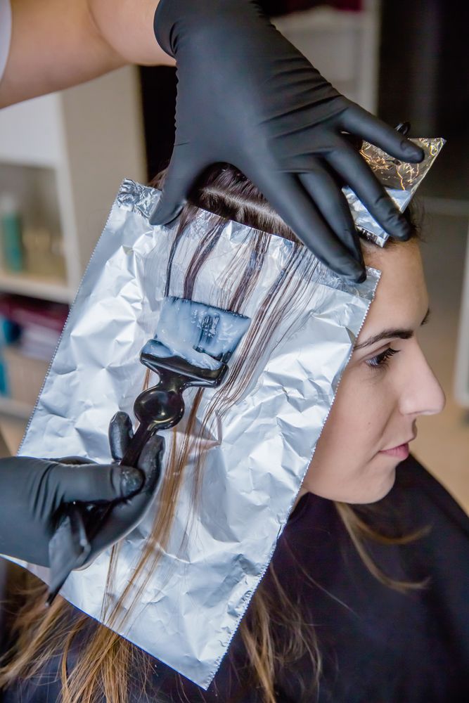 Closeup of hairdresser hands applying hair dye to client