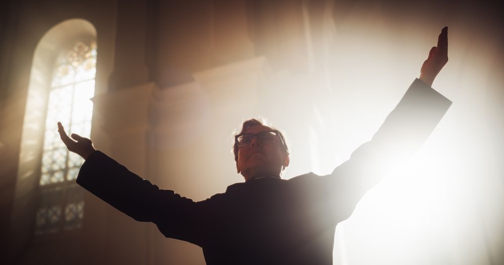 Portrait of Christian Priest Raising Hands In Blessing His Congregation while Praying In Church
