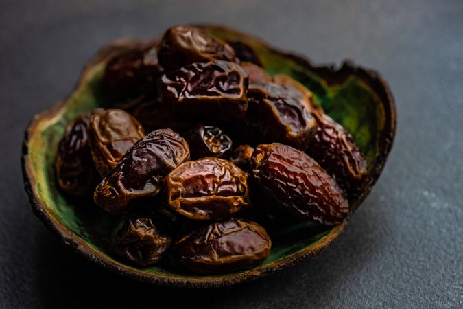 Organic dates in a bowl on dark table