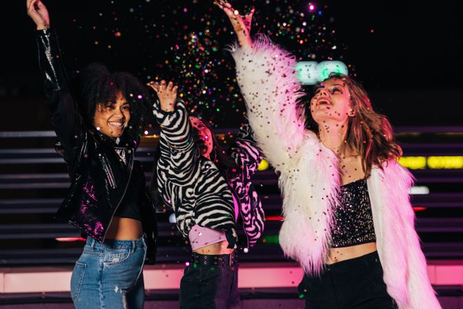 Multi-ethnic group of female friends throwing confetti on terrace