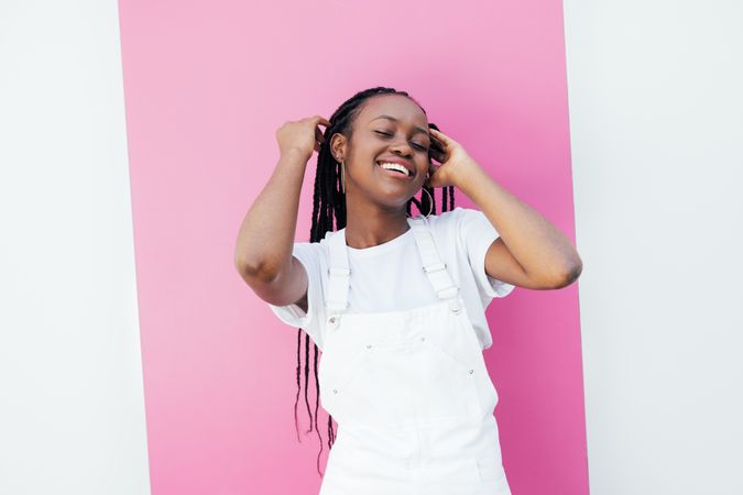 Black woman with long braids smiling touching her hair with her eyes closed