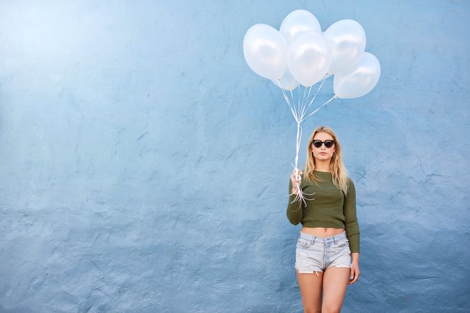 Shot of female model holding balloons against blue wall