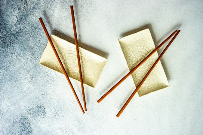 Top view of chopsticks on two rectangular ceramic dishes