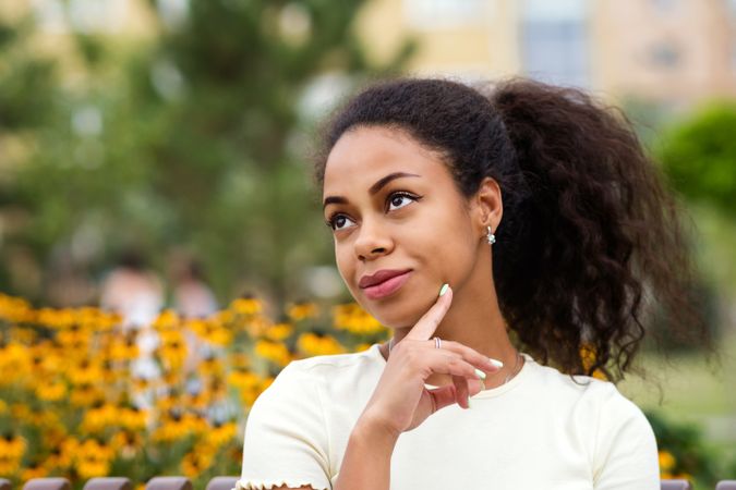Portrait of Black female contemplating on bench in front of flowers