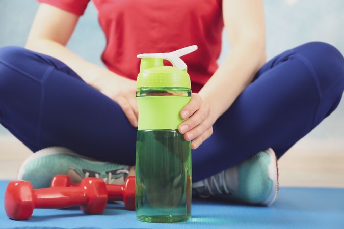 Person sitting crossed legs with green water bottle