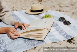 Cropped image of woman reading a book laying on textile at the beach 4dWGn5
