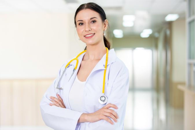 Portrait of proud female doctor with stethoscope smile in arms crossed