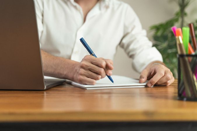 Close-up of a man writing or signing a document at his office desk.