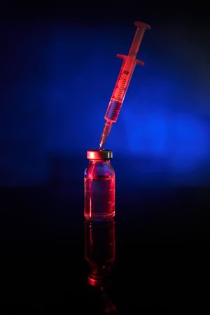 Red medical injection with COVID vaccine in studio