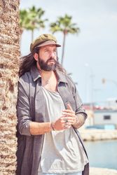 Bearded man standing near palm tree on beach