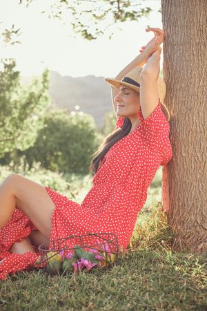 Smiling woman in red dress sitting on grass