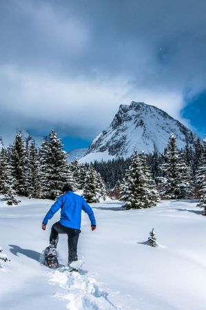 Man walking on snow covered ground near snow covered mountain