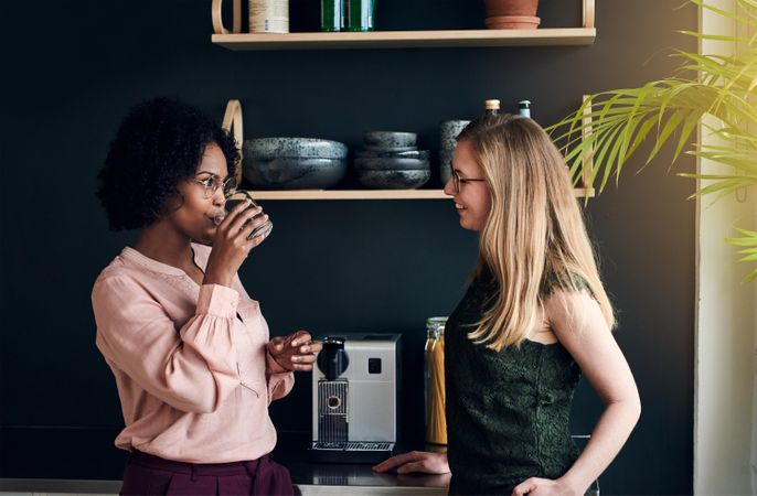 Two female businesswomen getting a drink in the office break room