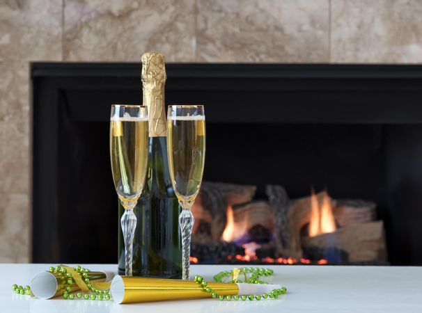 Happy New Year Celebration with Golden Champagne for two and glowing fireplace