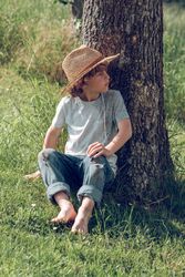 Boy leaning on tree trunk in park