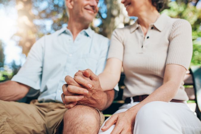 Cropped shot of mature couple holding hands while sitting on a bench