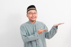 Asian Muslim man smiling showing product gesture in Ramadan