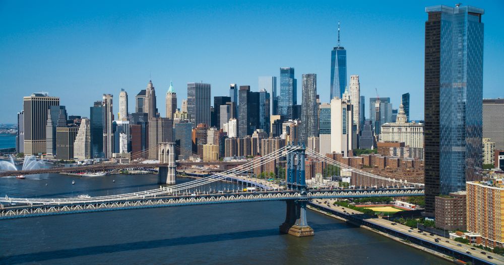 Aerial Cinematic Drone Scene Near the Manhattan and Brooklyn Bridges with NY Skyscrapers Cityscape. Beautiful Sun Shining on a Warm Summer Day. Photo of Historic Architecture
