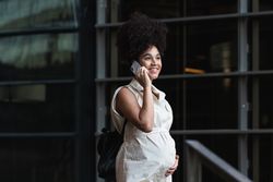Smiling Black pregnant woman talking on smartphone