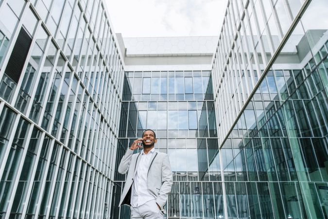 Elegant Black man talking smartphone near building