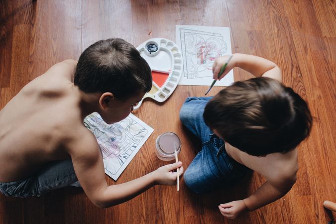 Two young boys coloring on the floor