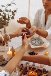 Cropped image of women sitting at table with gemstones and candles 4jzNv4
