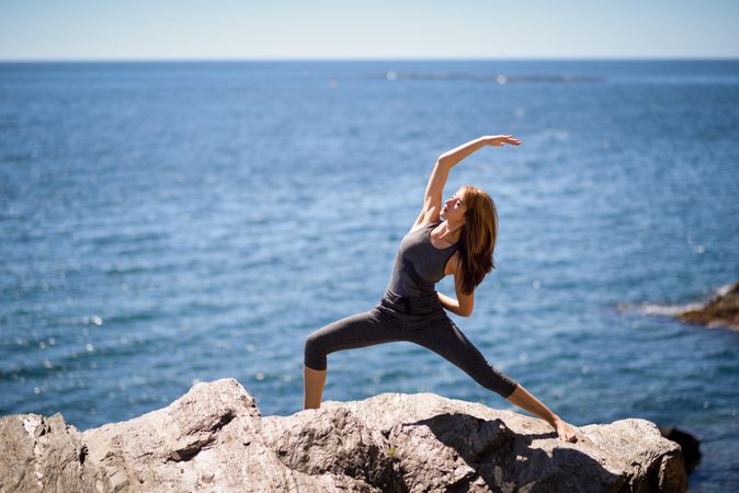 Young woman doing yoga on a rocky beach