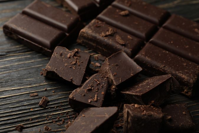 Chocolate pieces on wooden background, close up