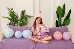 Young girl celebrating birthday at home with gifts and balloons.