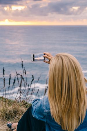 Female tourist taking shot of sea in twilight