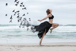 Young woman dancing with birds near sea