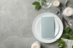 Composition of table setting with candles, leaves and cutlery on gray background