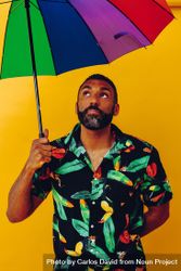 Black male looking up from under colorful umbrella 56qae0