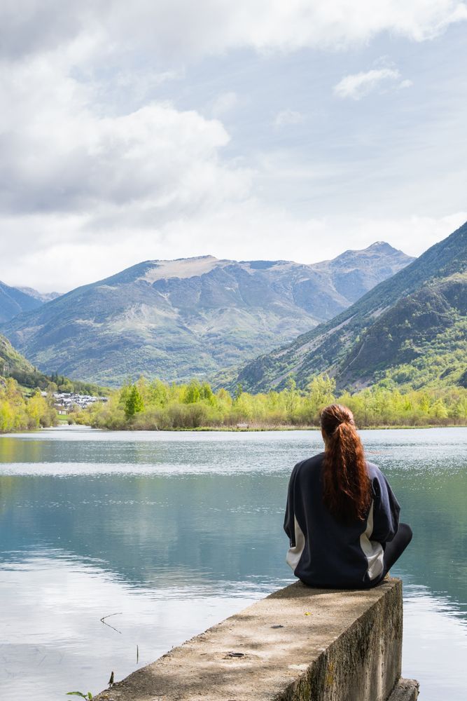 Carefree traveling woman enjoying freedom near lake in mountains