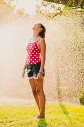 Cheerful teenager having fun with jet of water