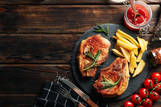 Composition with fried steaks on wooden background. Grilled food
