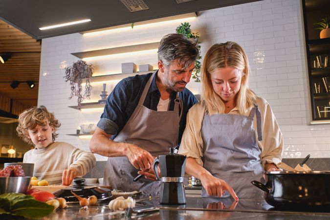 Parents cooking near son in kitchen