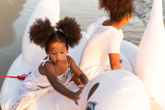 Two sisters in the water sitting on inflatable swan ring