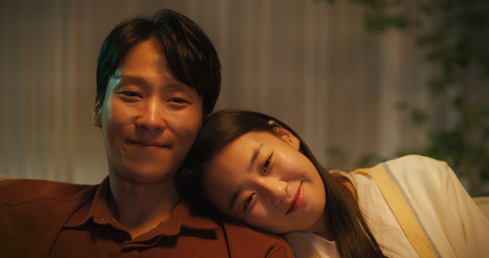 Portrait of a Young South Korean Couple Spending Time at Home, Sitting Together on a Sofa.