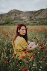 Woman sitting in field with poppies and daisies